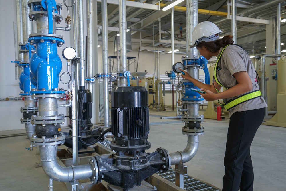 Young woman mechanical engineer inspection heating system on pressure gauge of industrial air compressor pump system at air compressor pump room